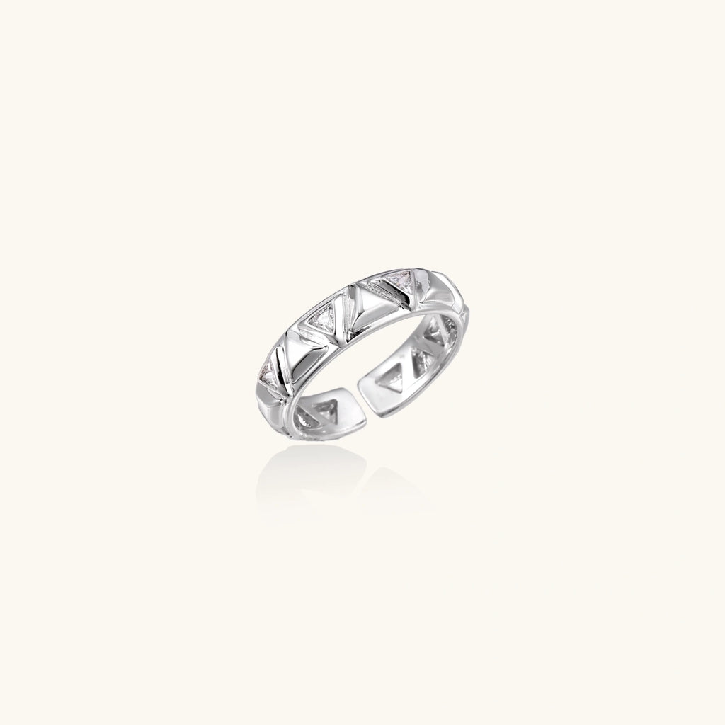 White gold adjustable ring with geometric triangle cutouts and zirconia stones on cream background